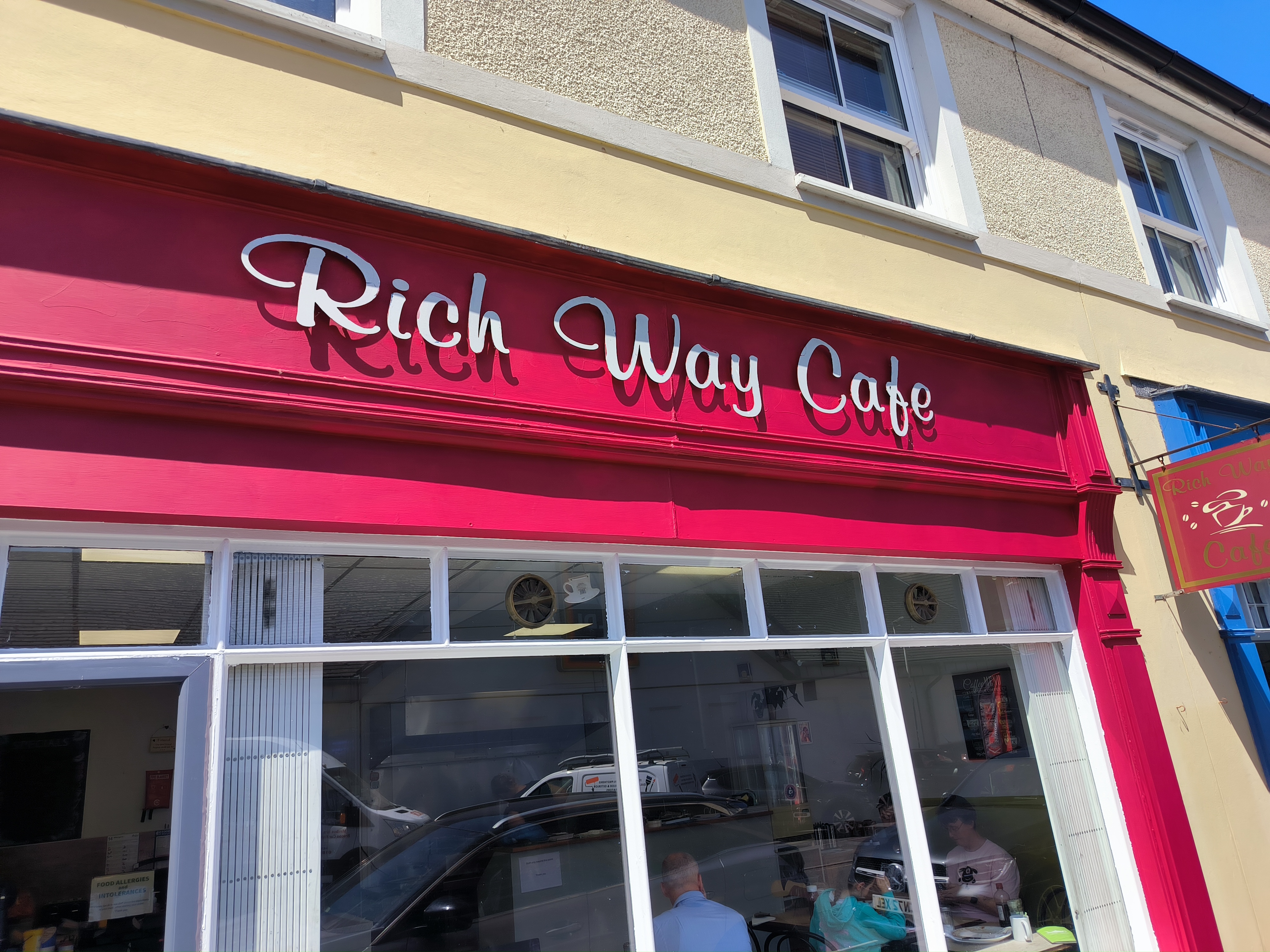 Rich Way Cafe storefront painted in deep raspberry red with new script-style signage